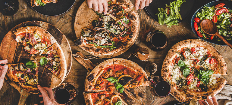 Top view of a Family and friends eating various kinds of Italian pizza over wooden table